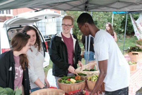 students stand with produce on table