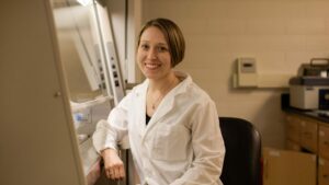 Lauren Anderson in white lab coat smiling in lab