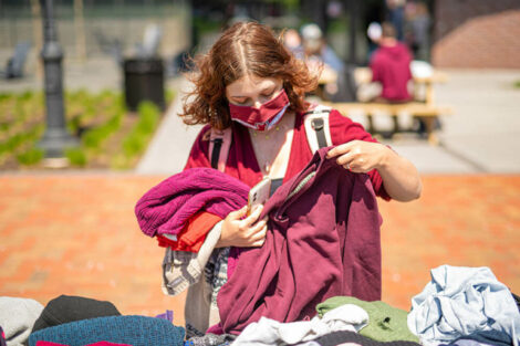 student in mask looks at clothing available at Pop-Up Thrift Shop