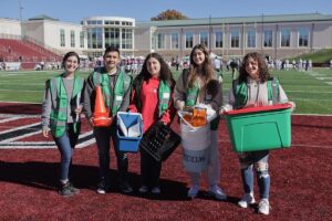 Students in green vests volunteer at the Game Day Challenge on Fisher Field. 