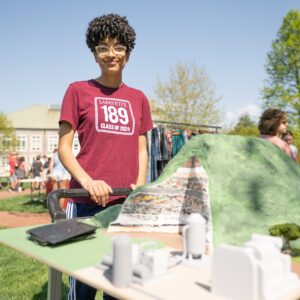 A student in a Class of 2024 shirt stands in front of a model of a green hill